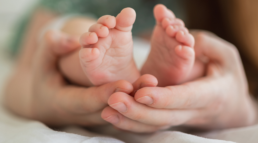 A fathers hands holding newborn baby feet